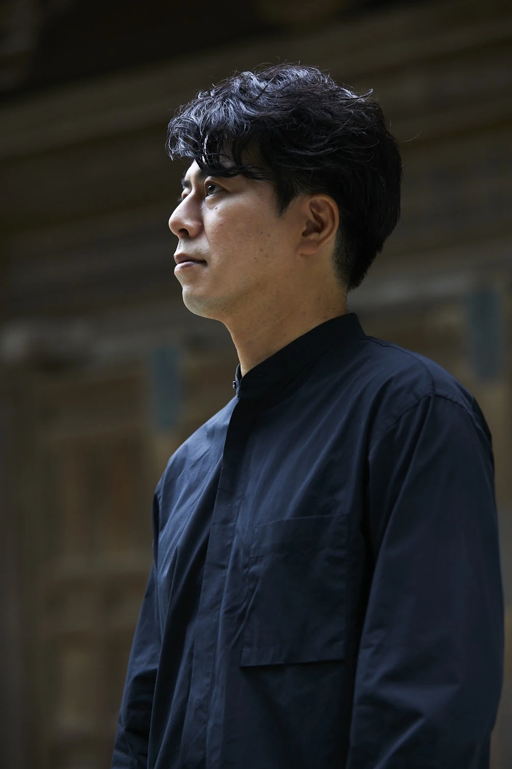 黒い服を着て、左に視線を向ける三橋鎌幽
